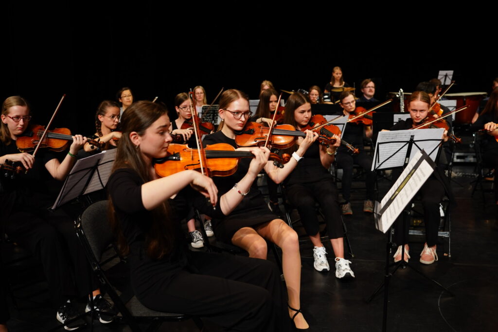Dunkle Konzertbühne mit jungen Musikern an Streichinstrumenten