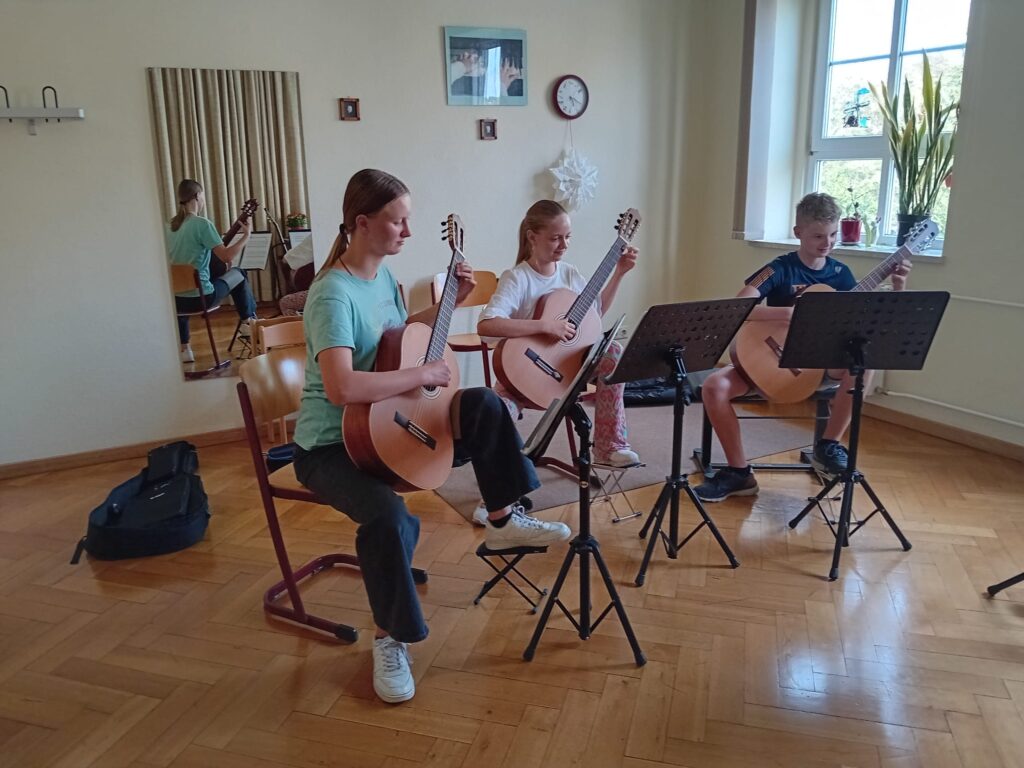Drei Jugendliche spielen Gitarre
