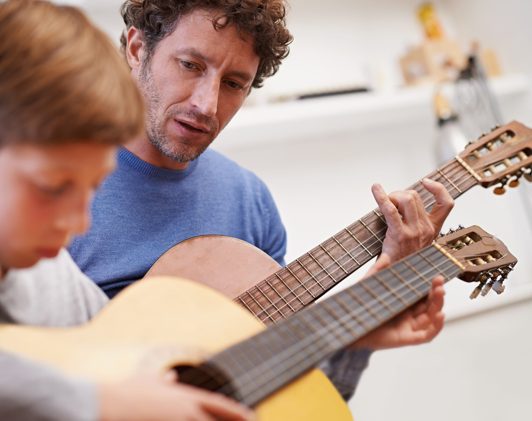Kind übt mit Lehrer Gitarre