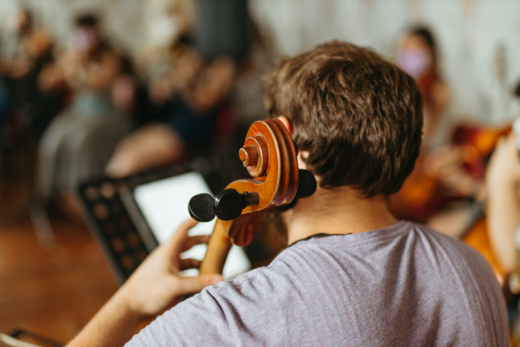 Blick über die Schulter von einem Musiker, der bei einem Auftritt mit einem Ensemble Kontrabass spielt